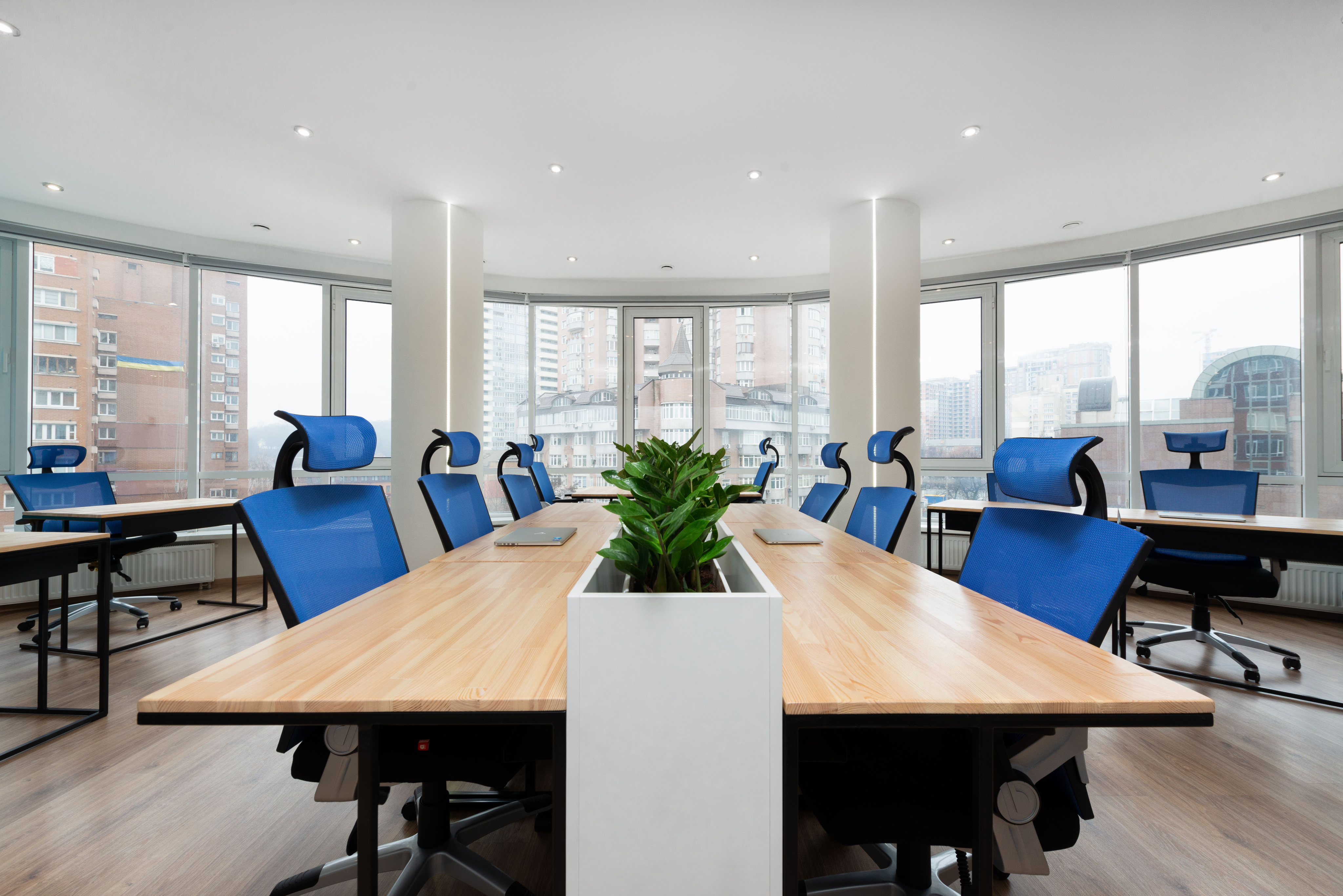 A modern conference room with blue office chairs around a wooden table